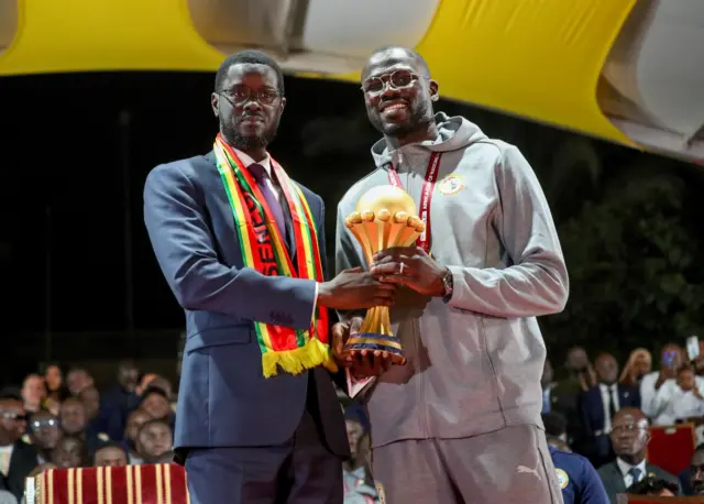 Senegalese president Bassirou Diomaye Faye and national team captain Khalidou Koulibaly holding the CAN 2025 trophy together