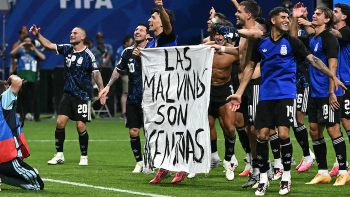 Des joueurs de soccer argentins tiennent une banderole où il est écrit « les Malouines sont argentines ».
